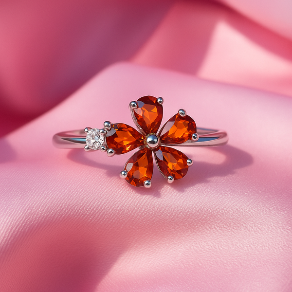 Ring with orange gemstones and a small diamond on a pink fabric background